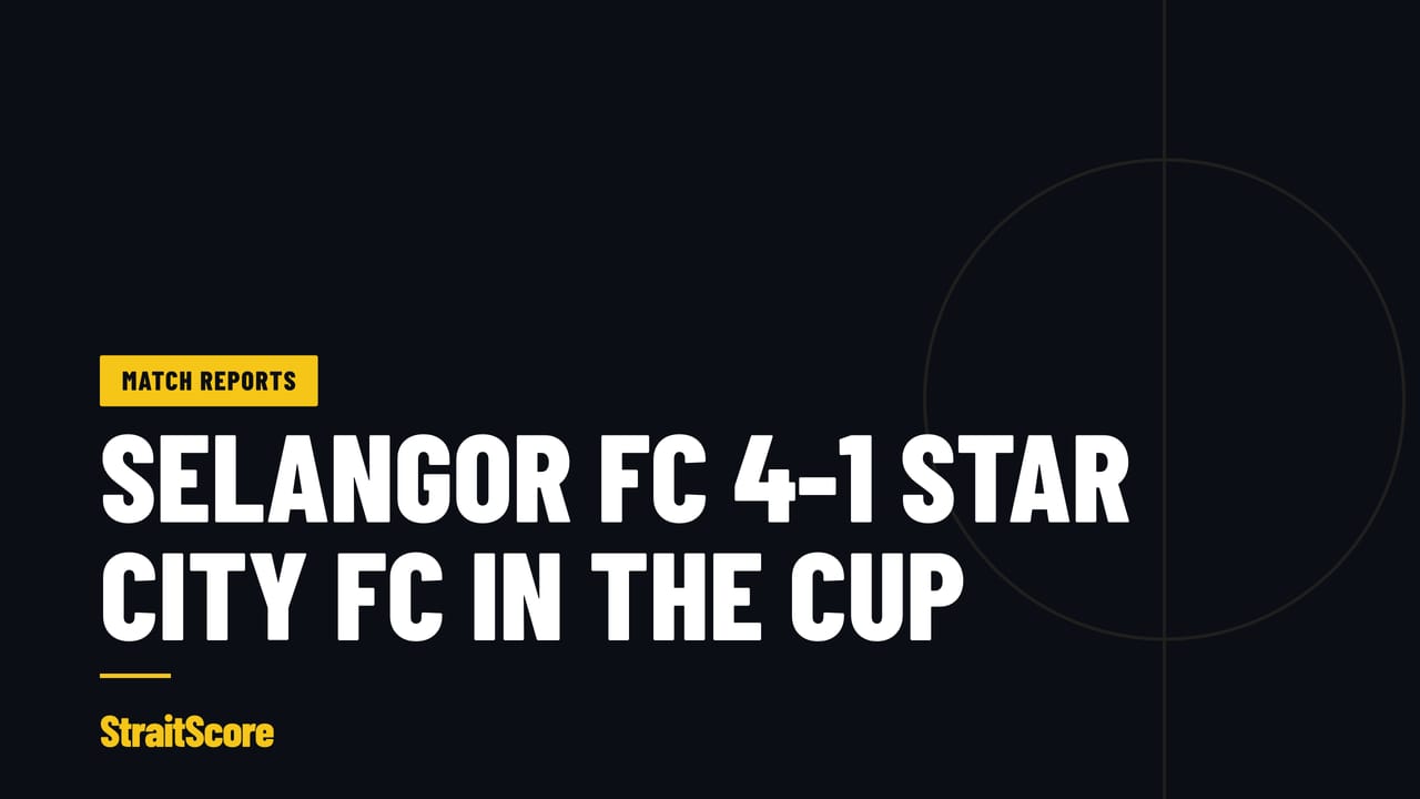 A goalkeeper picks the ball out of his net under floodlights at a Malaysian cup tie.